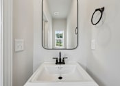 Thumbnail 39 of 56 - A white sink in a bathroom with a round mirror above it.