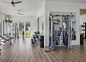 Thumbnail 25 of 47 - A spacious gym with a variety of equipment and a ceiling fan.