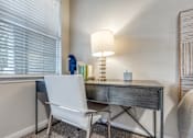 Thumbnail 11 of 30 - A white chair sits in front of a desk with a lamp on it.