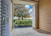 Thumbnail 28 of 30 - A view from a covered walkway looking out to a tree and shrubs.