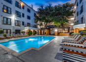Thumbnail 25 of 37 - a swimming pool at night in front of an apartment building