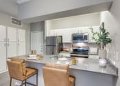 Thumbnail 9 of 37 - a kitchen with stainless steel appliances and a counter with chairs