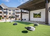 Thumbnail 35 of 47 - A patio area with a green lawn and a white wall with a picture on it.