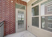 Thumbnail 31 of 33 - A white door with a window above it and a brick wall to the left.