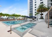 Thumbnail 21 of 66 - a swimming pool with chaise lounge chairs and palm trees in front of a tall building