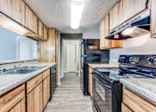 Thumbnail 19 of 27 - a kitchen with wood cabinets and black appliances and a sink