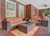 Thumbnail 22 of 30 - A patio with a striped couch and a table with a plant on it.