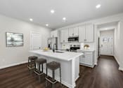 Thumbnail 41 of 56 - A kitchen with white cabinets and a white island with three stools.