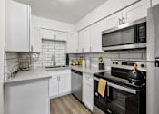 Thumbnail 3 of 26 - A modern kitchen with white cabinets and stainless steel appliances.