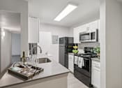 Thumbnail 15 of 38 - A modern kitchen with black appliances and white cabinets.