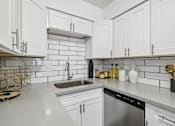 Thumbnail 4 of 26 - A kitchen with white cabinets and a stainless steel dishwasher.