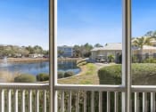 Thumbnail 13 of 30 - A view from a balcony looking out at a pond, houses, and a clear blue sky.