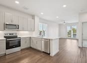 Thumbnail 36 of 57 - A kitchen with white cabinets and a wooden floor.