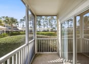 Thumbnail 14 of 30 - A balcony with a white railing and glass doors overlooking a green lawn.
