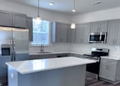 Thumbnail 30 of 32 - A modern kitchen with a large island in the center.