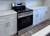 Thumbnail 32 of 32 - A kitchen with white cabinets and a black stove top oven.