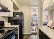 Thumbnail 4 of 20 - kitchen with black appliances and granite counter tops and a view of the living room