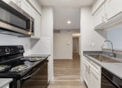 Thumbnail 14 of 20 - a kitchen with white cabinets and black appliances and a sink