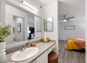 Thumbnail 21 of 37 - a bathroom with a sink and a mirror and a bed