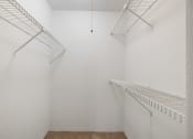 Thumbnail 11 of 37 - a walk in closet with white walls and shelves and a wire rack on the wall