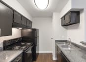 Thumbnail 12 of 37 - an empty kitchen with granite counter tops and black appliances