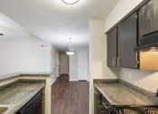 Thumbnail 13 of 37 - an empty kitchen with granite counter tops and dark cabinets