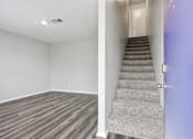 Thumbnail 5 of 23 - A room with a staircase leading to a door.