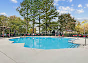Thumbnail 23 of 45 - A large swimming pool surrounded by trees and a fence.
