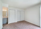 Thumbnail 8 of 19 - a bedroom with white walls and carpet and a door to a bathroom