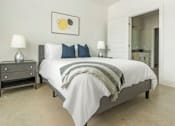 Thumbnail 6 of 11 - A bedroom with a bed, nightstand, and lamp.