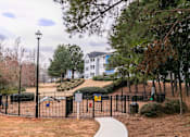 Thumbnail 10 of 31 - a park with a fence and a building in the background