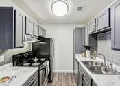 Thumbnail 21 of 31 - A kitchen with a black stove top oven and a black refrigerator.
