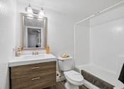 Thumbnail 7 of 26 - A white bathroom with a toilet, sink, and mirror.