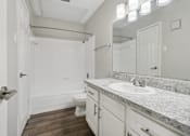 Thumbnail 11 of 24 - A bathroom with a white door, sink, and toilet.