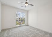 Thumbnail 40 of 57 - A room with a ceiling fan and carpeted floor.