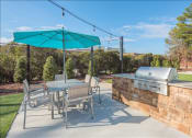 Thumbnail 10 of 14 - a patio with a grill and a table and chairs
