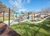 Thumbnail 9 of 14 - a playground with hammocks and tables and umbrellas