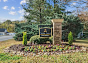 Thumbnail 32 of 45 - A sign for Tower Place Apartments is surrounded by flowers and greenery.