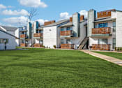 Thumbnail 2 of 38 - A row of modern apartment buildings with a green lawn in the foreground.