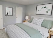 Thumbnail 4 of 19 - A bedroom with a bed, nightstand, and two framed pictures on the wall.