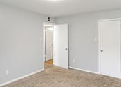 Thumbnail 5 of 19 - A room with two white doors and a carpeted floor.