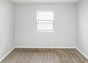 Thumbnail 6 of 19 - A room with a carpeted floor and a window with blinds.