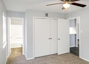 Thumbnail 9 of 19 - A room with a ceiling fan and three white doors.