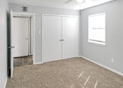 Thumbnail 2 of 19 - A room with a carpeted floor, two doors, and a window.