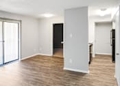 Thumbnail 14 of 19 - A spacious living room with a black refrigerator and wooden flooring.
