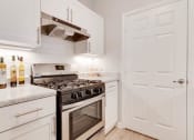 Thumbnail 12 of 17 - a kitchen with white cabinets and a stainless steel stove