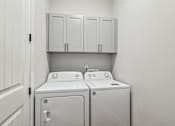 Thumbnail 10 of 38 - A white washing machine and dryer in a laundry room.