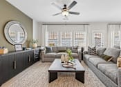 Thumbnail 8 of 37 - A living room with a grey couch, a coffee table, and a ceiling fan.