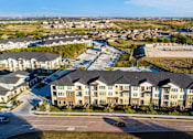 Thumbnail 3 of 25 - A large apartment complex with a parking lot in front.