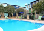 Thumbnail 32 of 36 - a swimming pool with chairs and umbrellas next to a building